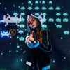 andre-hunter-ugjPgy2BQug-unsplash: A young woman posing in front of a Space Invaders background
