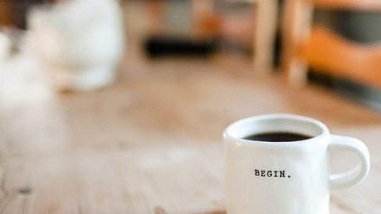 White coffee cup on kitchen table. Words " BEGIN " on the cup