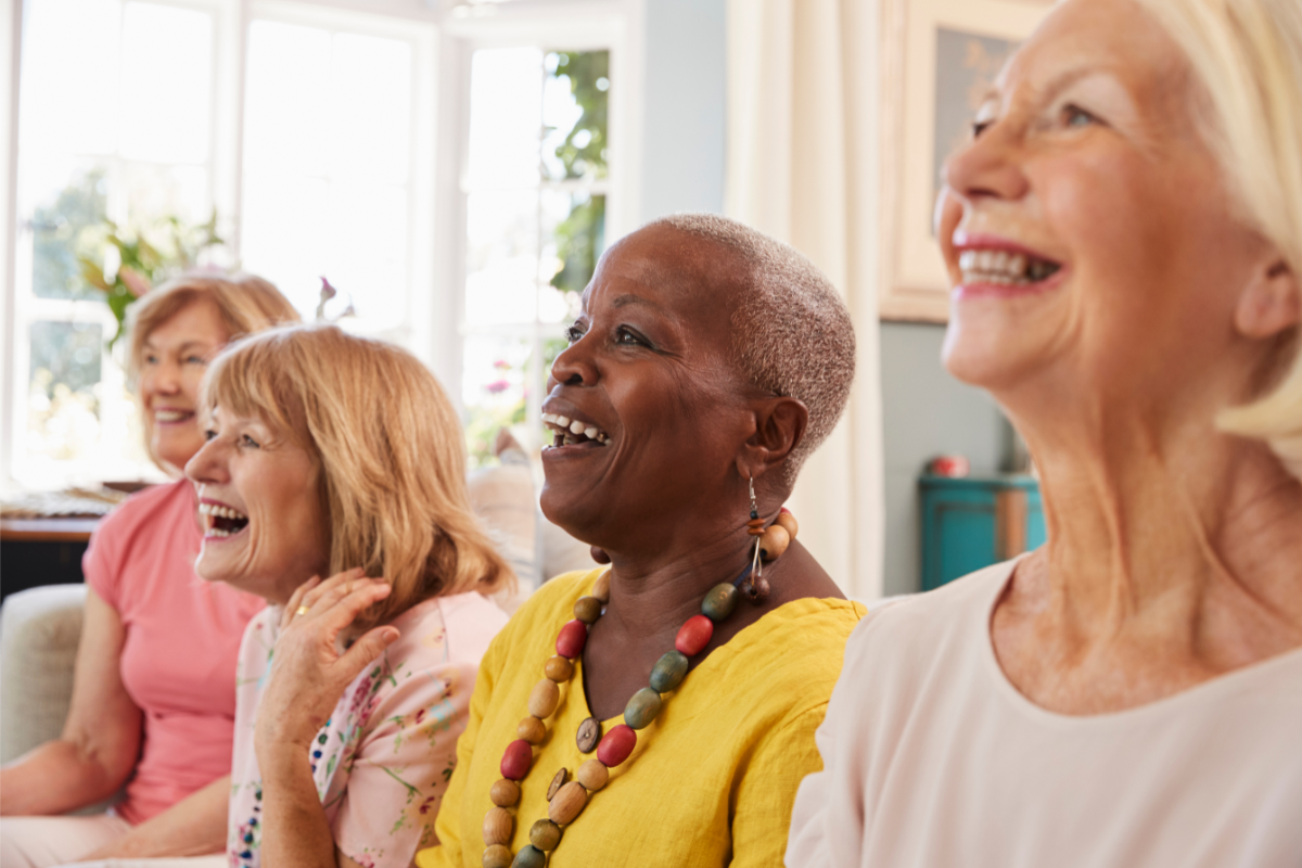 Four older women listening to a presentation and smiling